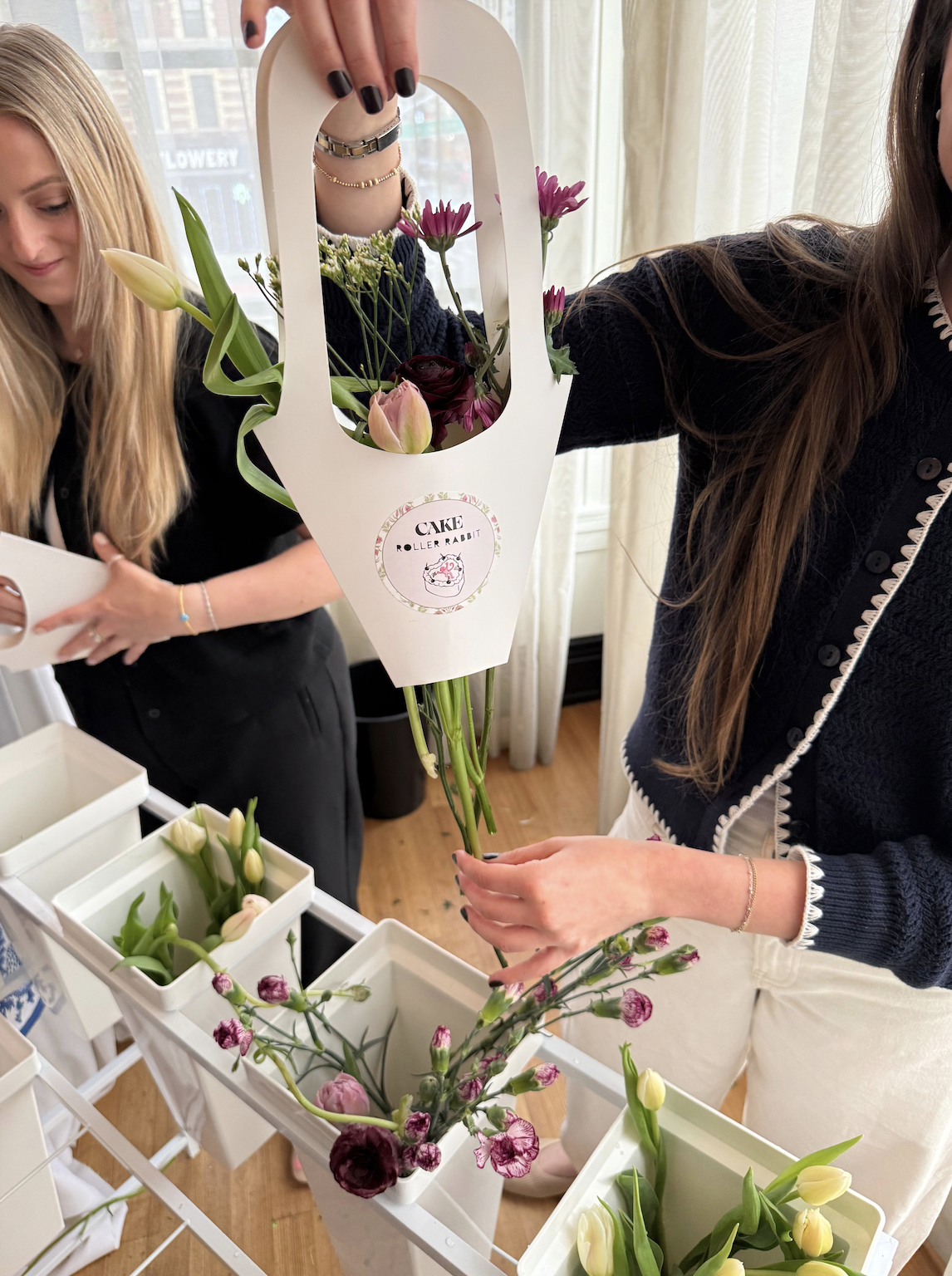 Guest creates a custom bouquet at the CAKE x Roller Rabbit bloom bar using tulips and pink flowers.